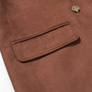 Gros plan d'un manteau en daim marron avec bouton marbré et rabat de poche surpiqué