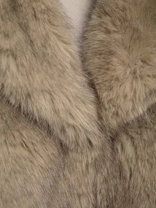 Vue macro de la fourrure synthétique dense sur un manteau d'hiver marron clair texturé