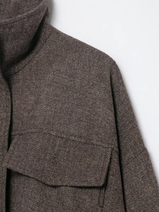 Close-up of herringbone tweed fabric showing standing collar and premium shoulder stitching