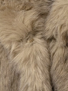 Détail de la fourrure synthétique brune et fermeture à crochet en métal doré sur un manteau