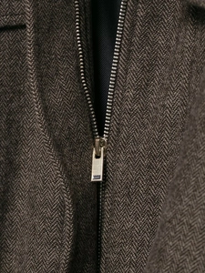 Detailed macro view of the silver zipper and herringbone wool texture on the bomber jacket