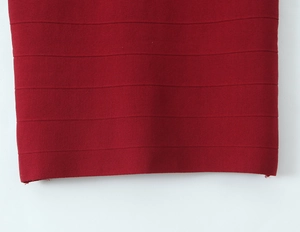 Macro detail of wine red ribbed knit fabric texture on the hem of a stylish dress