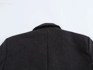 Close-up of wool-textured dark grey blazer collar and padded shoulder stitching detail