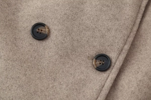 Macro detail of high-quality wool blend fabric and dark tortoiseshell buttons on coat