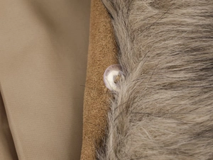 Detail of faux fur collar and brown suede texture with transparent button closure