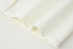 Close-up of white wool coat fabric showing high-quality texture and smooth hem detail