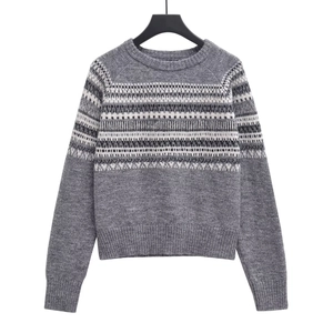 Detail of grey crewneck knit sweater showing black and white Fair Isle geometric pattern