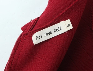 Macro shot of dark red ribbed knit fabric detail with hidden zipper and brand tag