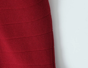 Macro shot of dark red knit fabric texture and horizontal pleated details of the dress
