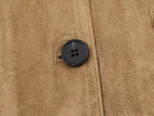 Macro detail of brown suede jacket showing black button and high-quality stitching