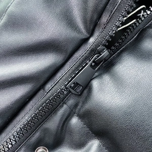 Close-up of black faux leather vest featuring matte finish and heavy-duty zipper