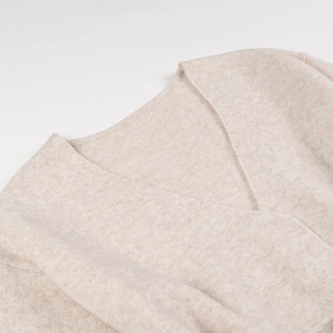 Gros plan sur le col en V croisé élégant et la texture en maille beige douce du gilet