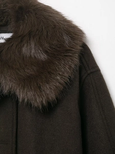Close-up of fluffy faux fur collar and textured wool blend fabric on dark brown coat