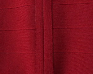 Close-up of dark red bandage knit fabric with horizontal texture and vertical stitching