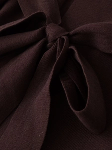 Nahaufnahme des gestrickten Schleifendetails am Taillengürtel des braunen Strickmantels