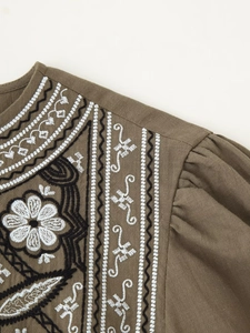 Detail of floral embroidery on olive cotton linen blouse with puffed sleeve design