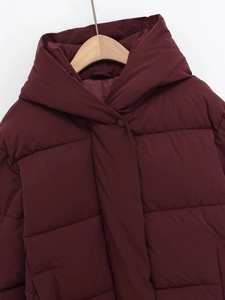 Détail de la doudoune à capuche bordeaux avec coutures horizontales et boutons-pression