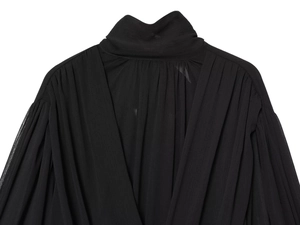 Détail du haut noir plissé avec col montant, décolleté en V et texture en mousseline