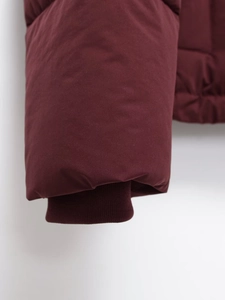 Détail du manteau bordeaux montrant les poignets côtelés coupe-vent et les coutures soignées