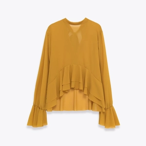 Detail of mustard yellow chiffon blouse featuring tiered ruffle hem and layered bell sleeves