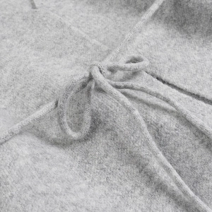 Gros plan détaillé sur la texture tricotée grise et le nœud du cordon du cardigan