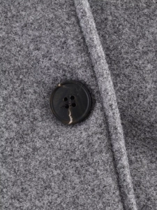 Gros plan détaillé du tissu en laine gris foncé avec un bouton effet marbre brun