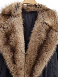 Close-up of a black winter jacket featuring a plush brown faux fur collar on a wooden hanger