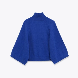 Detailed macro view of the royal blue knit texture and wide ribbed cuffs of the sweater
