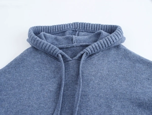 Detail of blue knitted hoodie showing the ribbed collar edge and matching drawstring