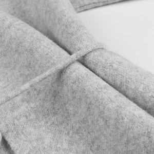 Détail du tissu en maille gris clair et ceinture à nouer assortie sur un gilet long