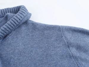 Detailed close-up of high chimney collar and shoulder seams on blue knitted sweater