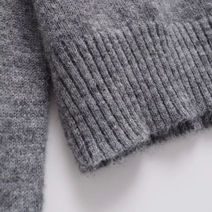 Close-up of thick grey knitted sweater featuring ribbed cuffs and soft fiber texture
