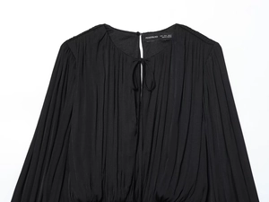 Détail d'un haut plissé noir avec encolure en trou de serrure, lien et texture de tissu