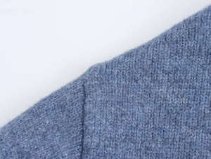 Close-up detail of soft blue knitted sweater showing high-quality stitching and texture