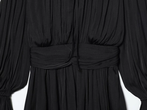 Détail d'une robe noire plissée avec décolleté à cordon et manches lanternes élégantes