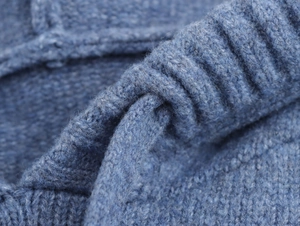 Close-up of the blue chunky knit fabric showing the detailed stitch and ribbed texture