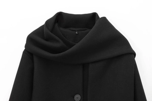Detailed close-up of a high turtleneck collar on a black wool coat with button detail