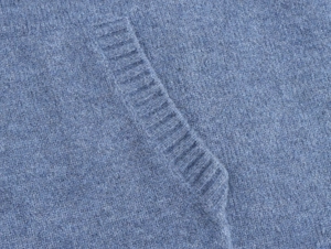 Close-up of light blue knit sweater showing fine texture and ribbed pocket detailing