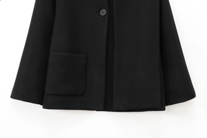 Detail of black wool coat featuring a round button and a classic square patch pocket