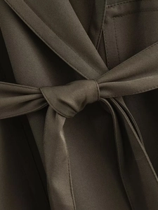 Macro view of olive green twill fabric tie belt with detailed knot on elegant trousers