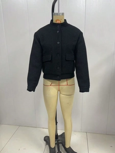 Detail of black tweed jacket featuring stand collar and single-breasted button closure