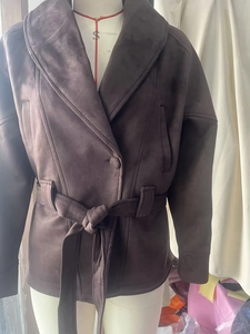 Détail d'une veste en suédine marron foncé avec revers et ceinture à la taille