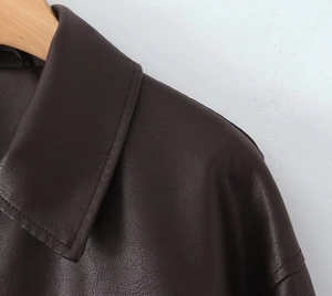 Detailed close-up of dark brown PU leather jacket with classic lapel and fine stitching