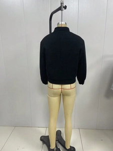 Rear view of a black stand collar jacket with ribbed hem on a mannequin