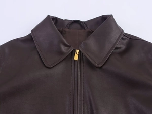 Primo piano del colletto della giacca in pelle marrone scuro con cerniera in metallo dorato