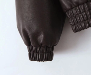 Close-up of elastic hem and cuffs on dark brown PU leather jacket with lychee texture