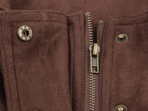 Macro detail of dark brown faux suede jacket with bronze zipper and star-patterned metal button