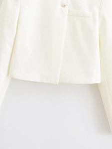 Détail d'un blazer court blanc montrant des coutures propres et une poche de poitrine