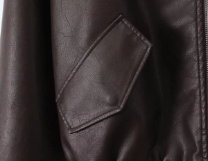 Close-up of deep brown PU leather jacket featuring flap pocket and stitching details