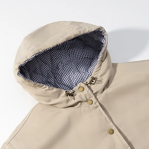 Detail of khaki hooded jacket featuring vintage brass buttons and blue gingham lining